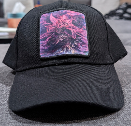 Black cap with a colorful cannabis leaf design on a gray surface