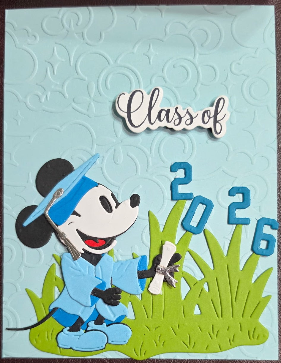 Graduation-themed card with a cartoon character in a cap and gown, 'Class of 2026' text, and grass design on a light blue background.