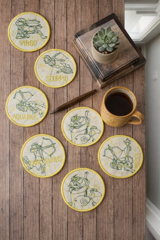 Picture of birth sign zodiac coasters on a table with a cup of coffee.